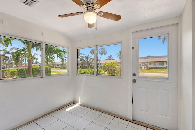 unfurnished sunroom with tile patterned floors, visible vents, and a wealth of natural light