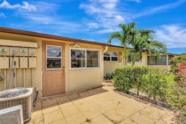 property entrance featuring cooling unit, a patio area, and stucco siding