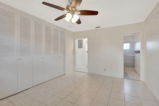 unfurnished bedroom featuring electric panel, a ceiling fan, visible vents, light tile patterned floors, and a closet