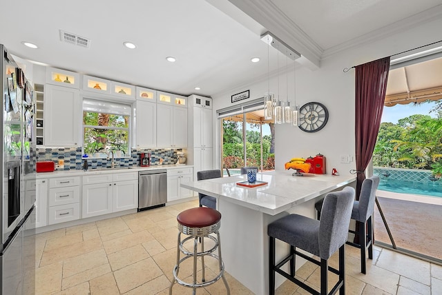 4474 Thornwood Cir, Palm Beach Gardens, FL 33418 - kitchen with dishwasher, a kitchen breakfast bar, decorative backsplash, ornamental molding, and white cabinetry