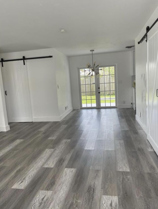interior space featuring baseboards, dark wood-style floors, a barn door, and an inviting chandelier