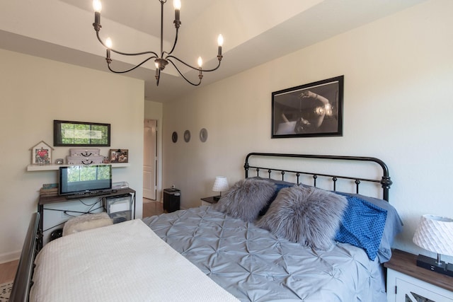 bedroom with baseboards, wood finished floors, and a notable chandelier