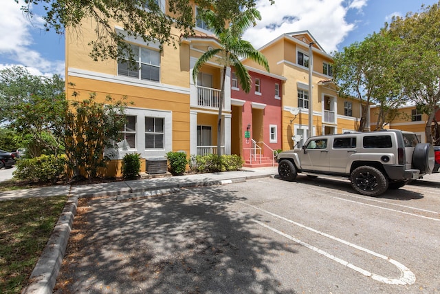exterior space with uncovered parking, stucco siding, and cooling unit