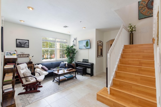 living room with visible vents, arched walkways, stairs, and recessed lighting