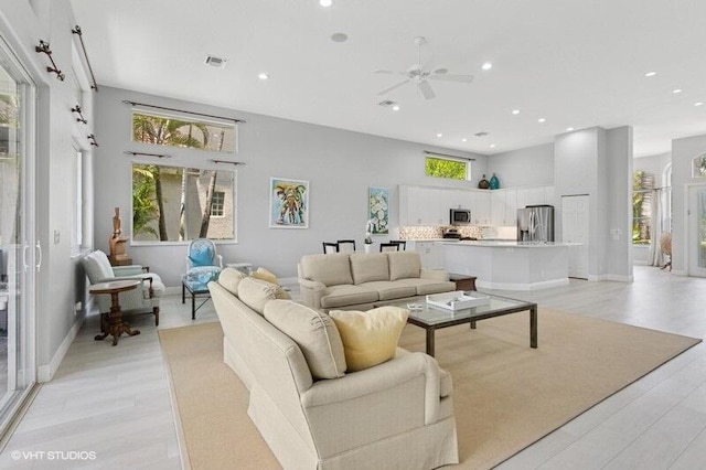 living area featuring recessed lighting, light wood-type flooring, ceiling fan, and baseboards