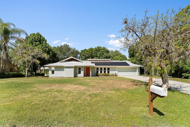 view of front of property featuring concrete driveway, metal roof, a front lawn, and a garage