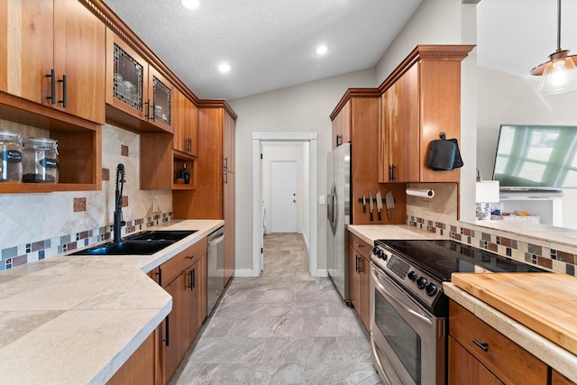 kitchen featuring brown cabinetry, a sink, light countertops, glass insert cabinets, and stainless steel appliances