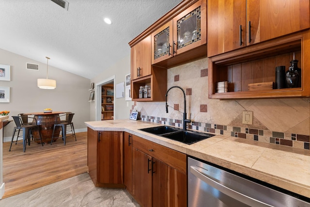 kitchen with tasteful backsplash, dishwasher, a sink, lofted ceiling, and glass insert cabinets