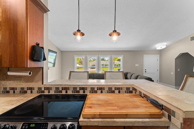 kitchen with decorative backsplash, a textured ceiling, pendant lighting, stainless steel electric range oven, and light countertops
