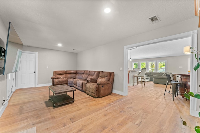 living room featuring visible vents, baseboards, and light wood-type flooring