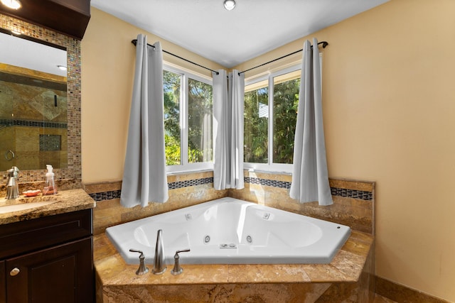 bathroom with vanity, a shower stall, and a tub with jets