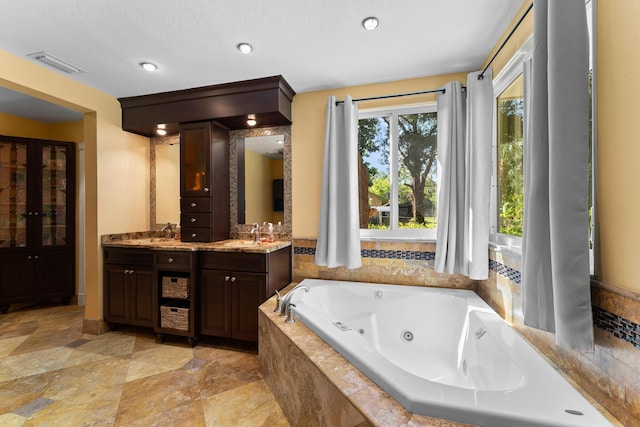 full bathroom featuring double vanity, a whirlpool tub, a sink, and visible vents