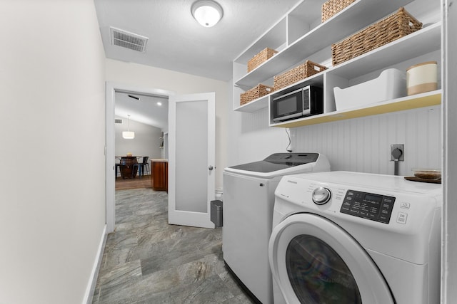 clothes washing area featuring washing machine and clothes dryer, laundry area, visible vents, and baseboards