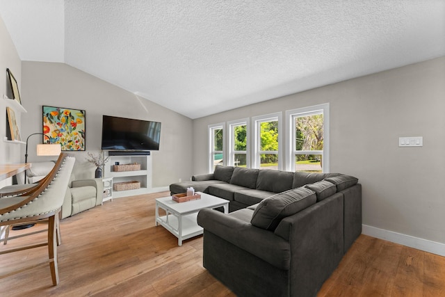 living room with baseboards, a textured ceiling, vaulted ceiling, and wood finished floors