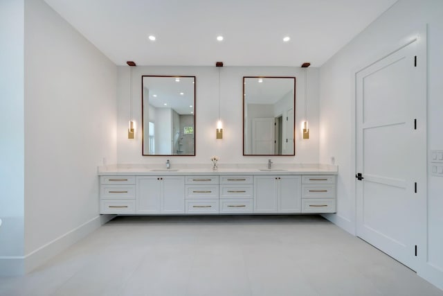 bathroom with double vanity, baseboards, recessed lighting, and a sink