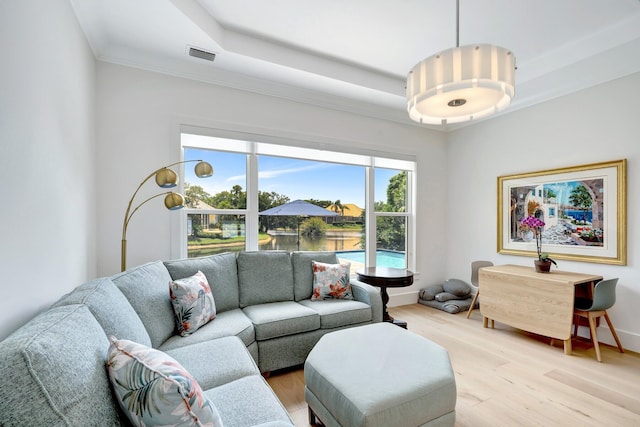 living room with a raised ceiling, baseboards, light wood-type flooring, and visible vents