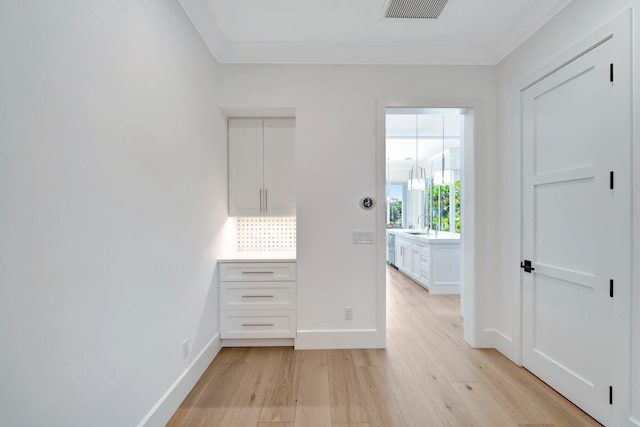 unfurnished bedroom with crown molding, baseboards, light wood-type flooring, and visible vents
