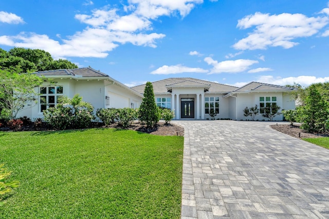 prairie-style house with stucco siding, decorative driveway, and a front lawn
