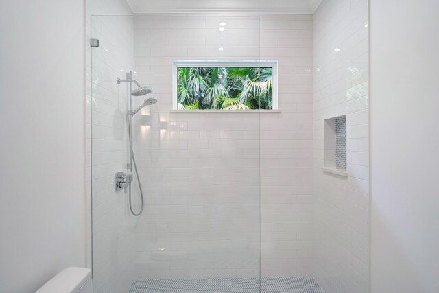 full bathroom with toilet, a tile shower, and ornamental molding
