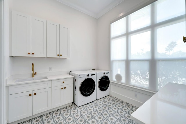 washroom featuring washing machine and clothes dryer, crown molding, cabinet space, a sink, and baseboards
