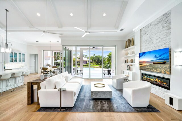living room featuring ceiling fan, ornamental molding, a stone fireplace, and a wealth of natural light