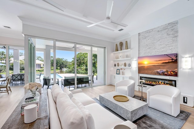 living area featuring light wood-style floors, crown molding, built in features, and ceiling fan