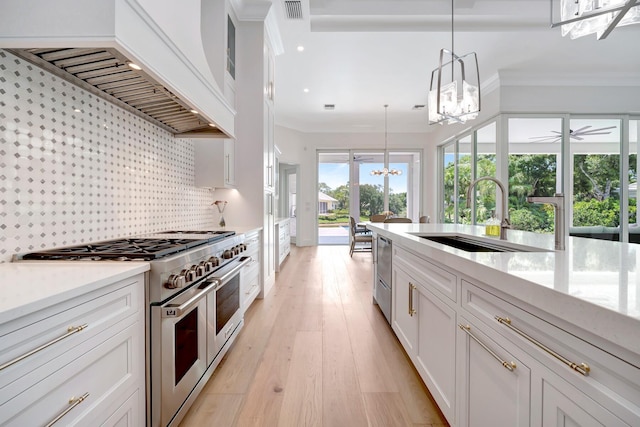 kitchen featuring visible vents, appliances with stainless steel finishes, a sink, custom exhaust hood, and a notable chandelier