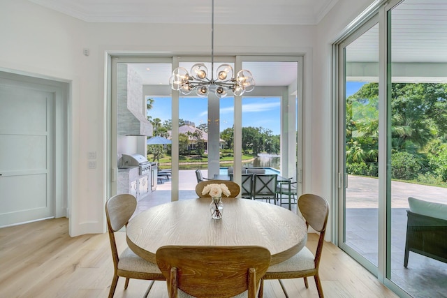 dining room with ornamental molding, light wood-type flooring, and a notable chandelier