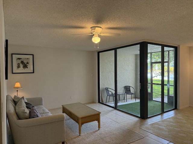 living area featuring ceiling fan, a textured ceiling, expansive windows, light tile patterned floors, and baseboards