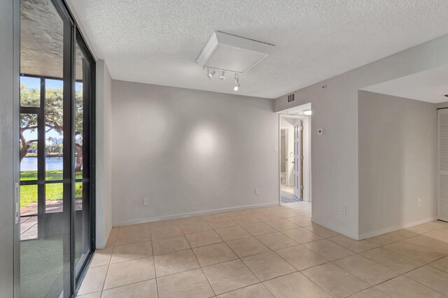 unfurnished room with visible vents, a textured ceiling, light tile patterned floors, and expansive windows