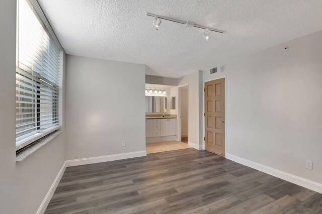 interior space with track lighting, baseboards, wood finished floors, and visible vents