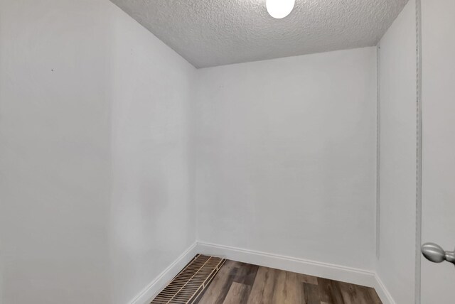 empty room featuring baseboards, a textured ceiling, and dark wood-type flooring
