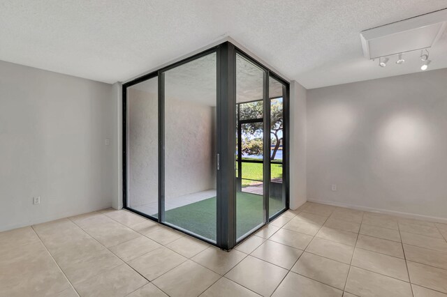 tiled empty room with a textured ceiling and expansive windows
