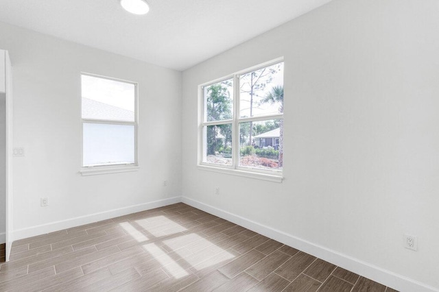 unfurnished room with baseboards and wood finish floors