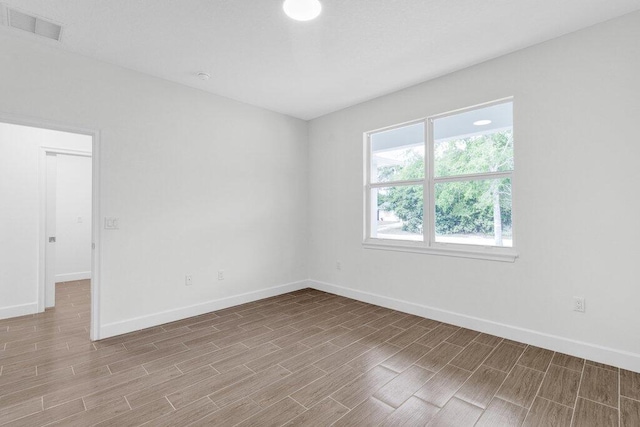 unfurnished room featuring baseboards, wood tiled floor, and visible vents