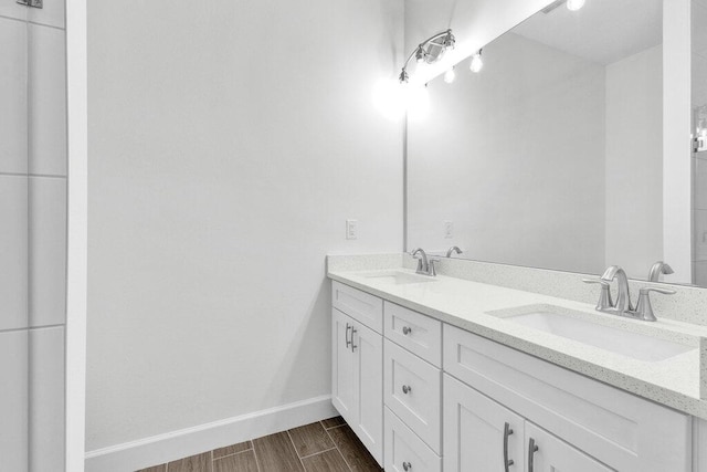 bathroom with a sink, baseboards, double vanity, and wood finished floors