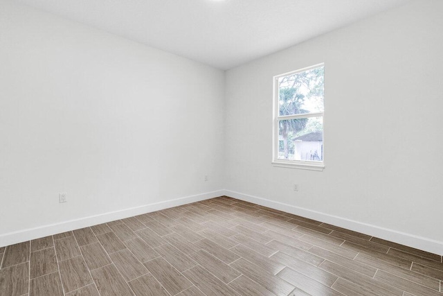 unfurnished room with baseboards and wood finish floors