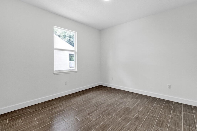 spare room featuring baseboards and dark wood-type flooring