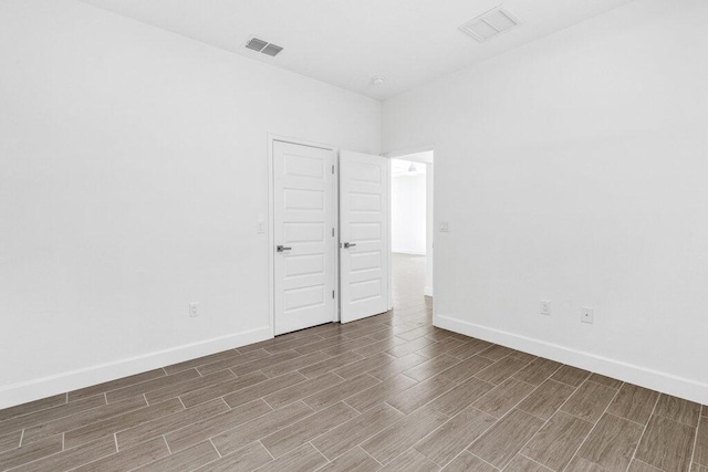 spare room with baseboards, wood finished floors, and visible vents