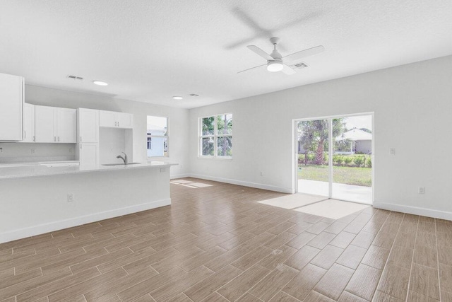 unfurnished living room featuring baseboards, visible vents, and light wood-style floors