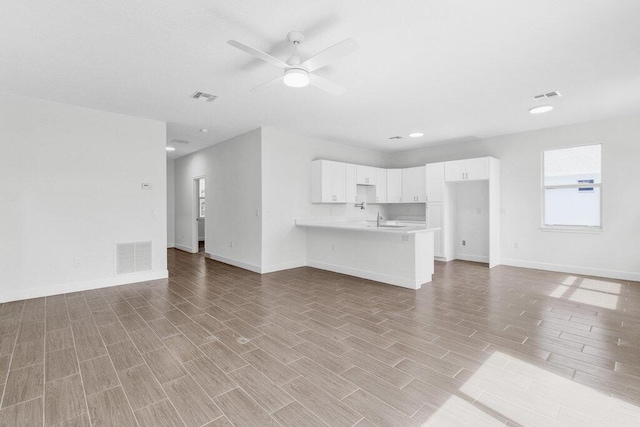 unfurnished living room with visible vents, a ceiling fan, and wood finished floors