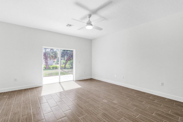 spare room featuring visible vents, wood finished floors, baseboards, ceiling fan, and a textured ceiling