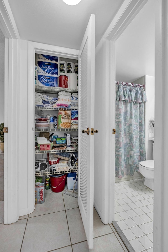 interior space featuring tile patterned flooring, curtained shower, and toilet