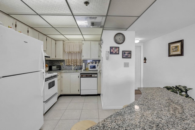 kitchen with a paneled ceiling, light tile patterned floors, light stone counters, a toaster, and white appliances