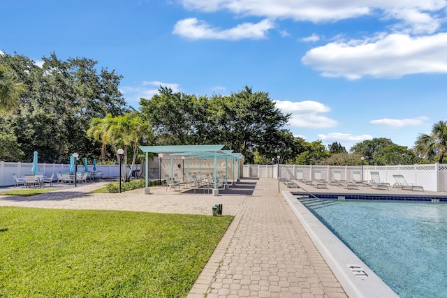 community pool with a lawn, fence, and a patio area