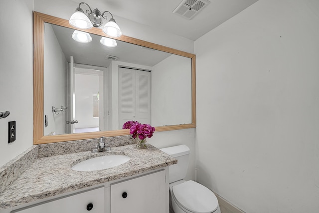 bathroom with vanity, toilet, and visible vents