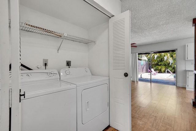laundry area featuring laundry area, washing machine and dryer, light wood finished floors, and a textured ceiling
