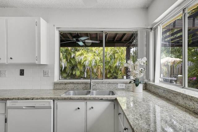 kitchen featuring decorative backsplash, a healthy amount of sunlight, white dishwasher, white cabinets, and a sink