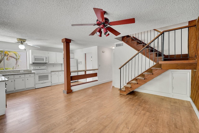 unfurnished living room with visible vents, a ceiling fan, light wood finished floors, and decorative columns