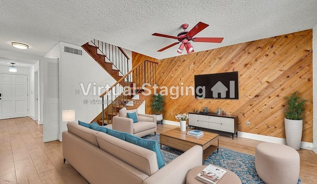 living room with ceiling fan, stairs, baseboards, wood finished floors, and visible vents